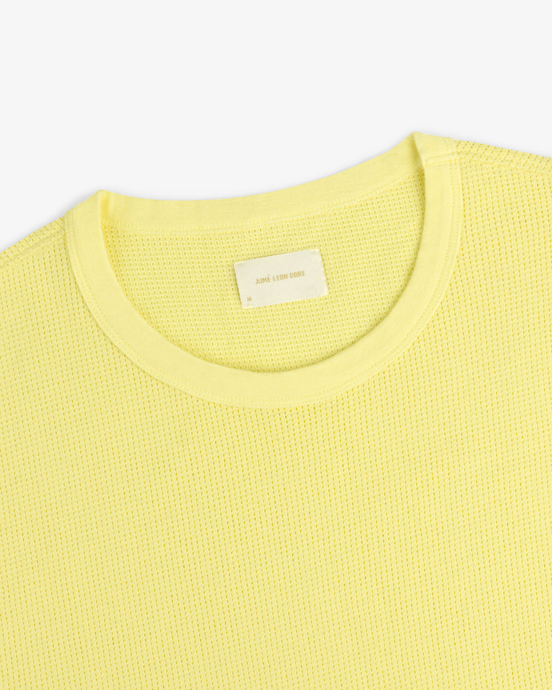 Close-up of a light yellow Mesh Muscle Tank with textured fabric and a visible white tag at the collar.