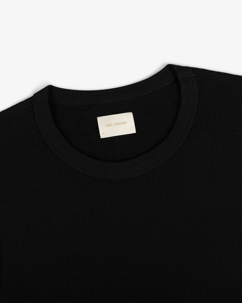 Close-up of a black Mesh Muscle Tank with a beige label inside the collar on a plain white background.