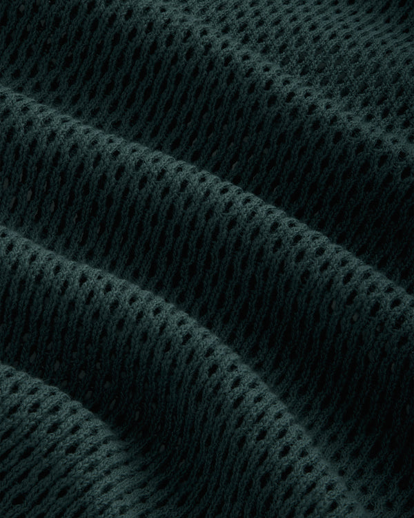 Close-up of Mesh Tank Top fabric, with dark texture and evenly spaced holes creating ridges and waves.