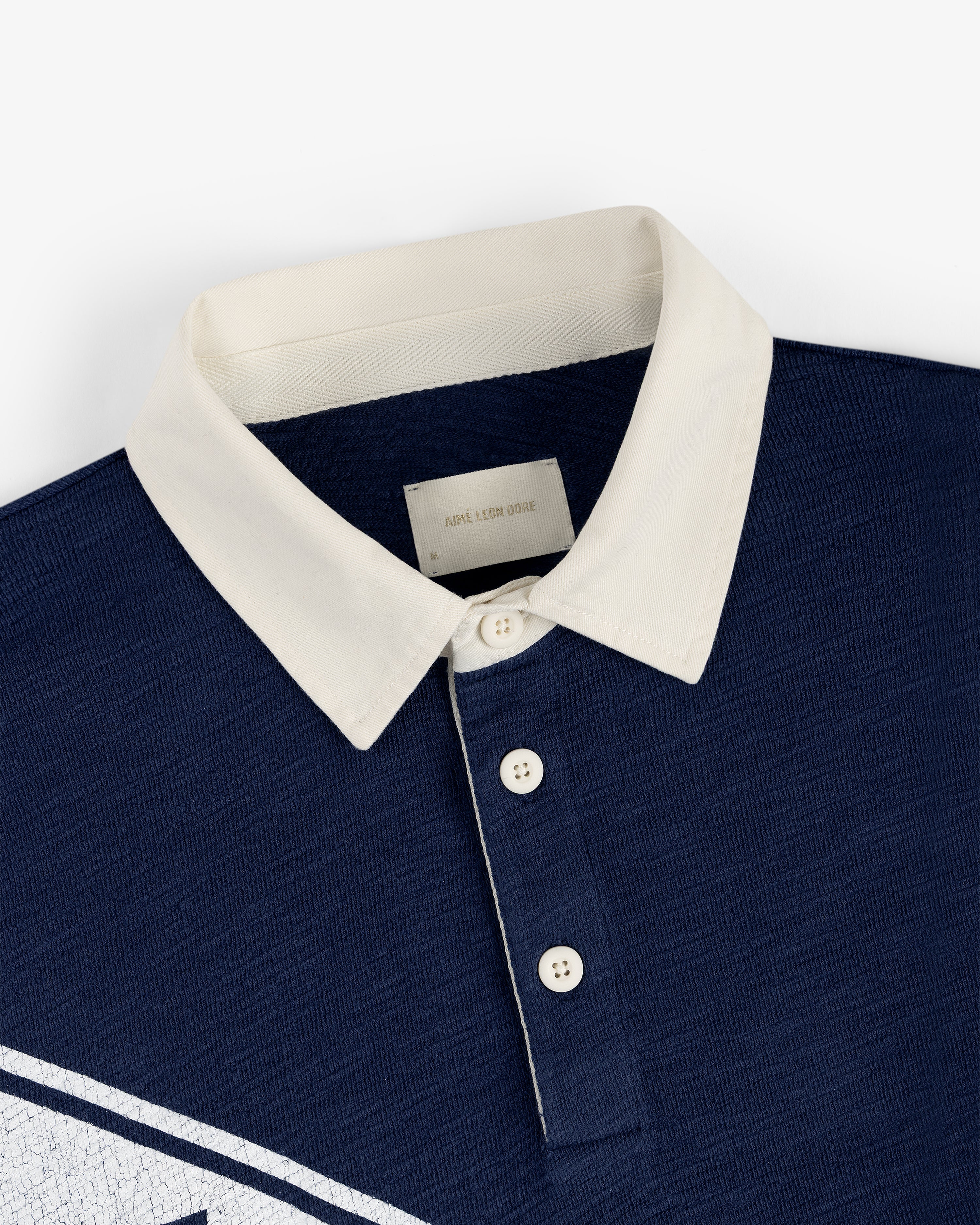 Vintage Slub Rugby in navy blue with white buttons and a white collar, flat laid on a white background.