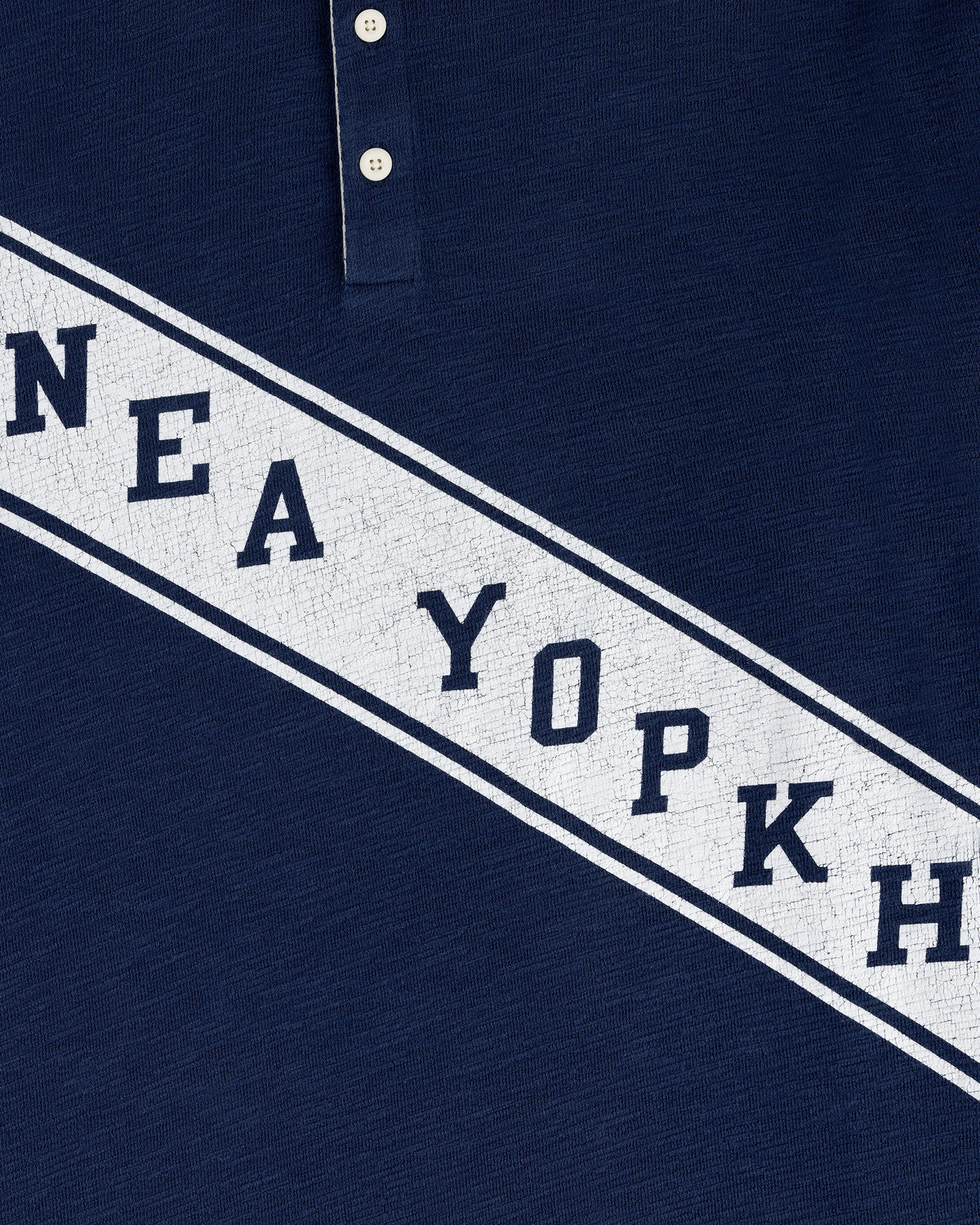 Close-up of the Vintage Slub Rugby in navy, featuring bold white cracked diagonal text reading NEA YOPKH.