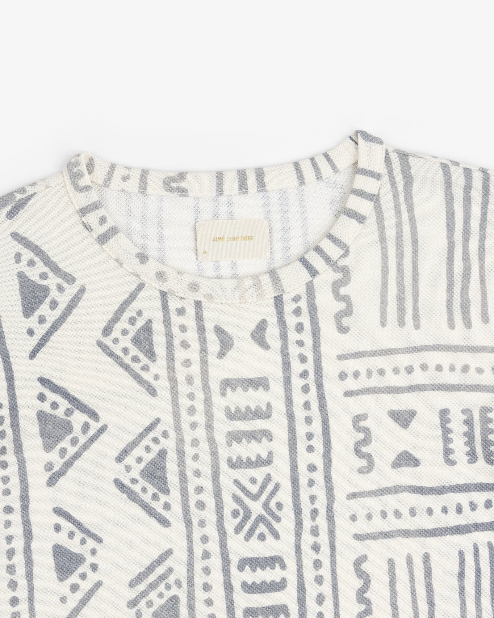Close-up of the Long-Sleeve Mesh Tapestry Tee featuring gray geometric and tribal-inspired prints on white.