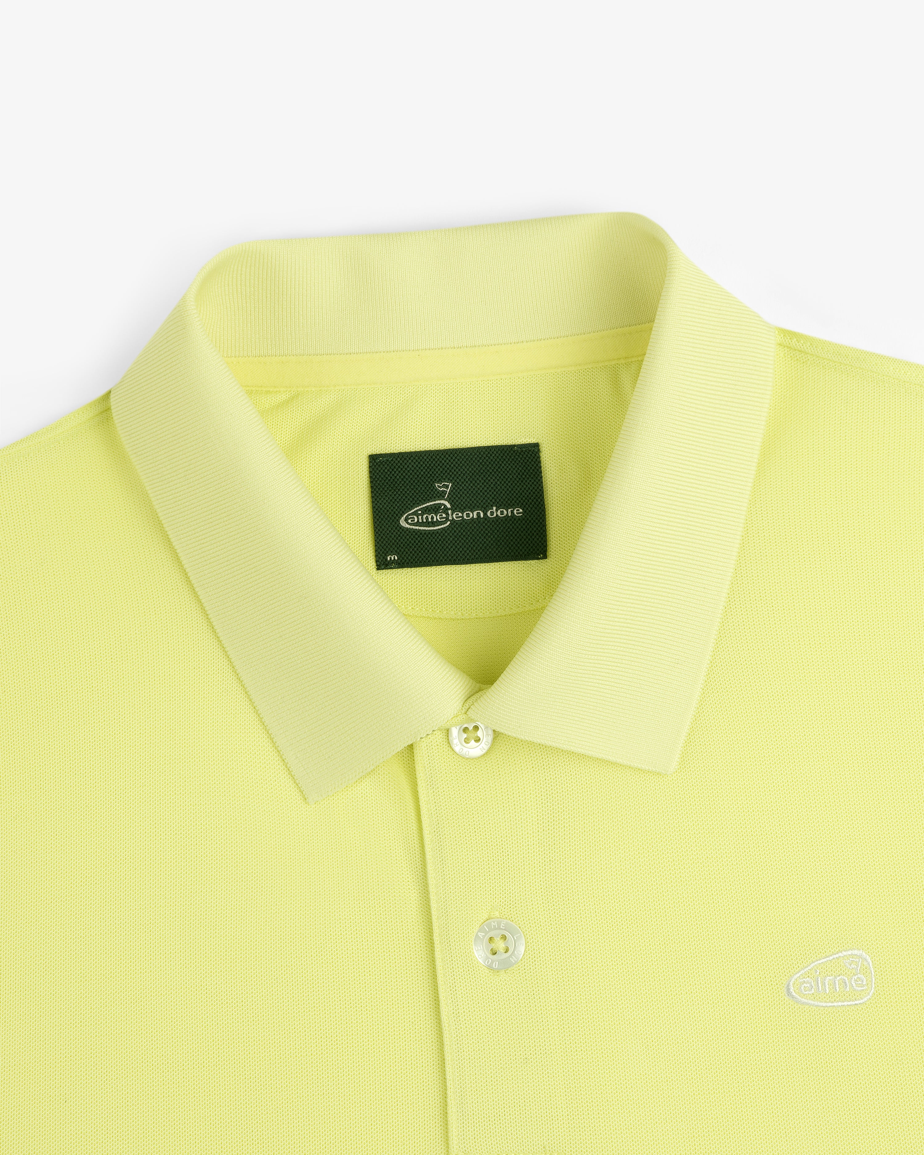 Lemon yellow ALD Golf Polo with a collar, two buttons, and a dark green Aimé Leon Dore neck tag.