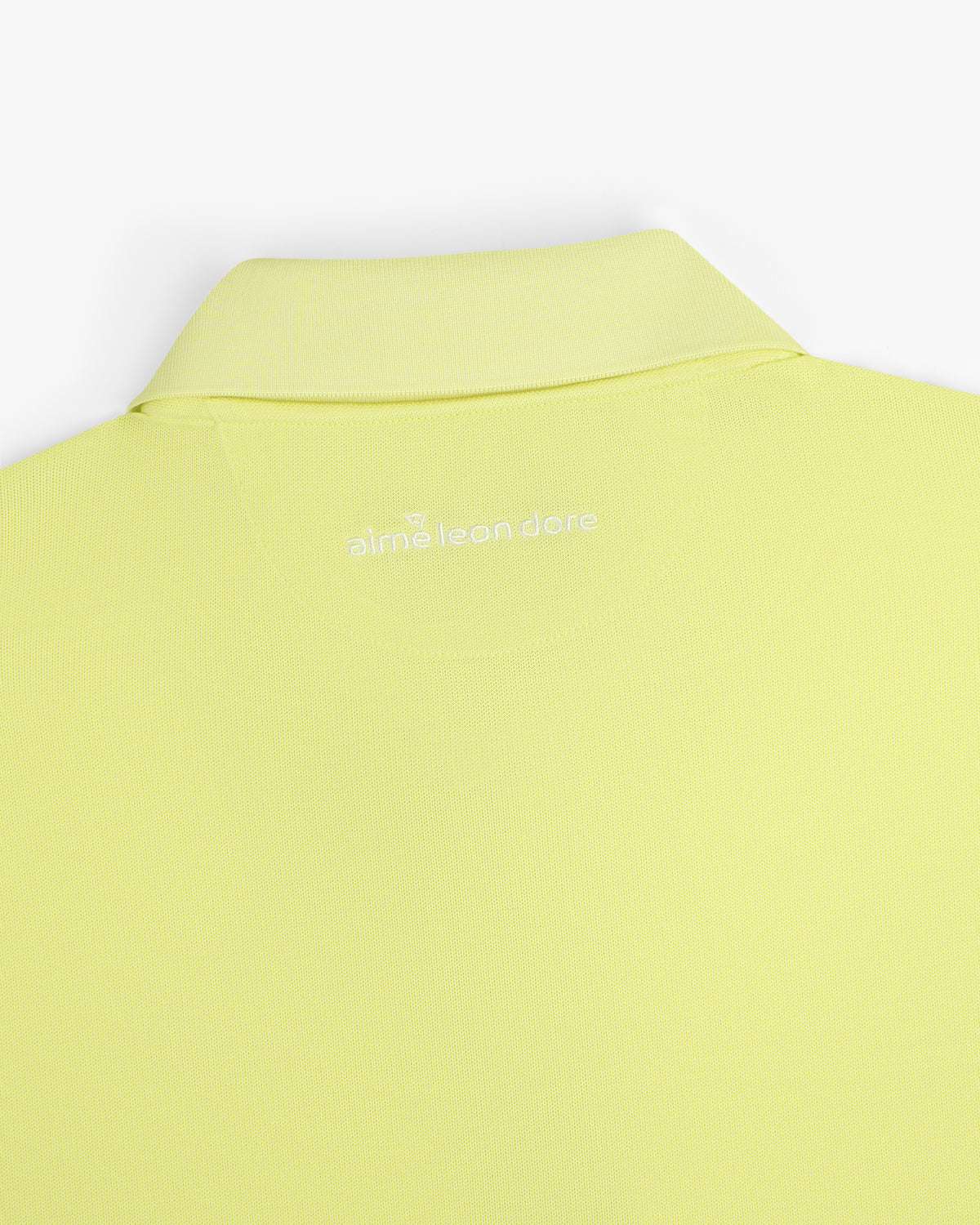 Close-up of the back collar of a light yellow ALD Golf Polo with "aimé leon dore" embroidered in white.