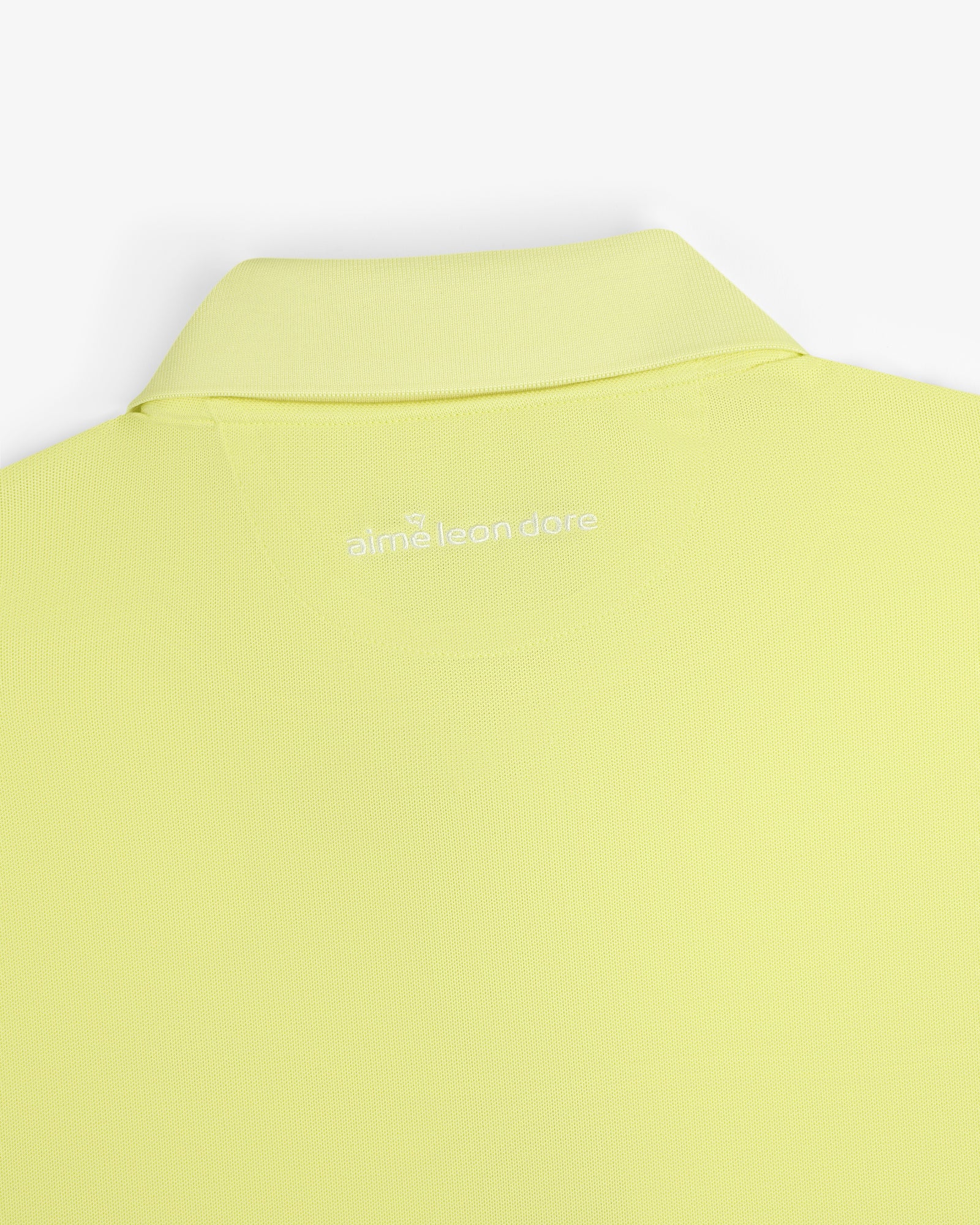 Close-up of the back collar of a light yellow ALD Golf Polo with "aimé leon dore" embroidered in white.