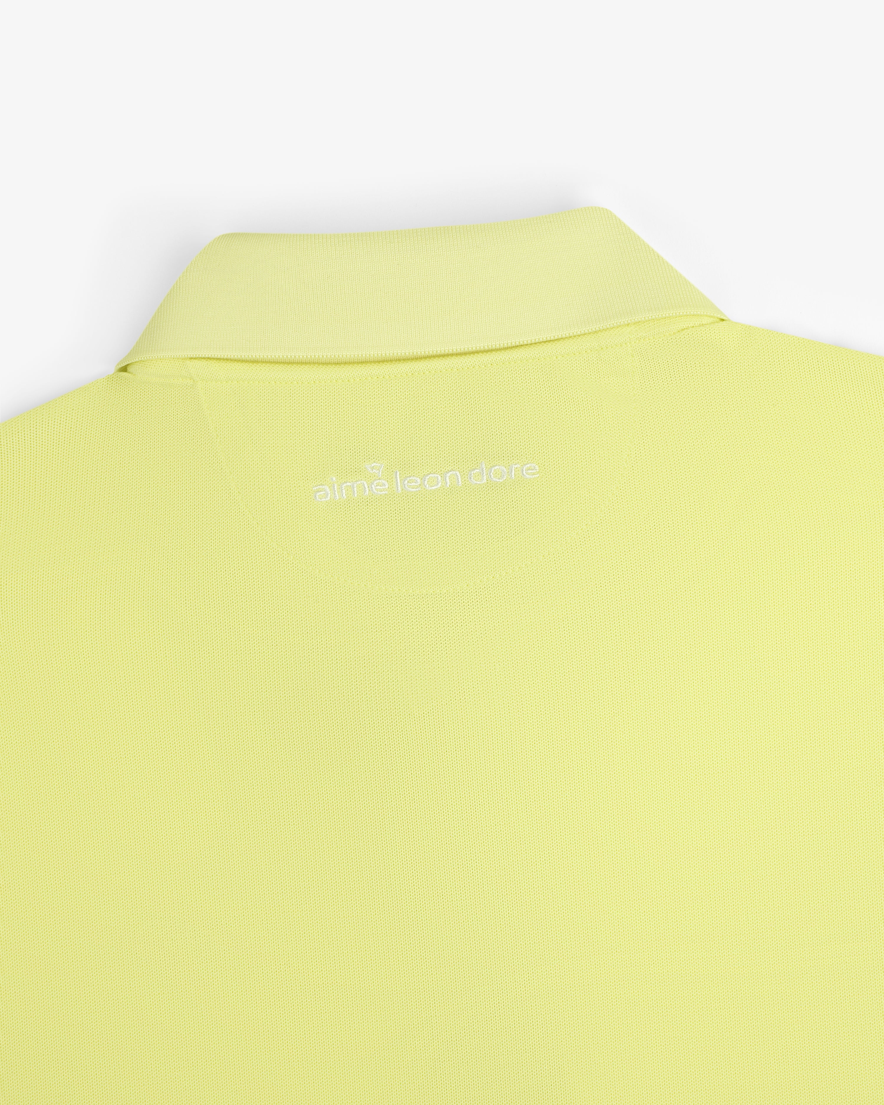 Close-up of the back collar of a light yellow ALD Golf Polo with "aimé leon dore" embroidered in white.