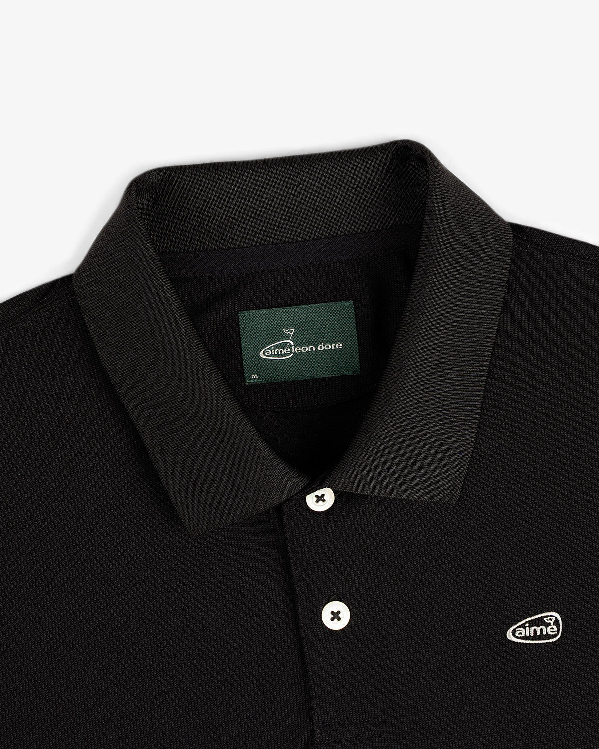 ALD Golf Polo: black collared shirt with white buttons and Aimé Leon Dore logo patch on the chest.