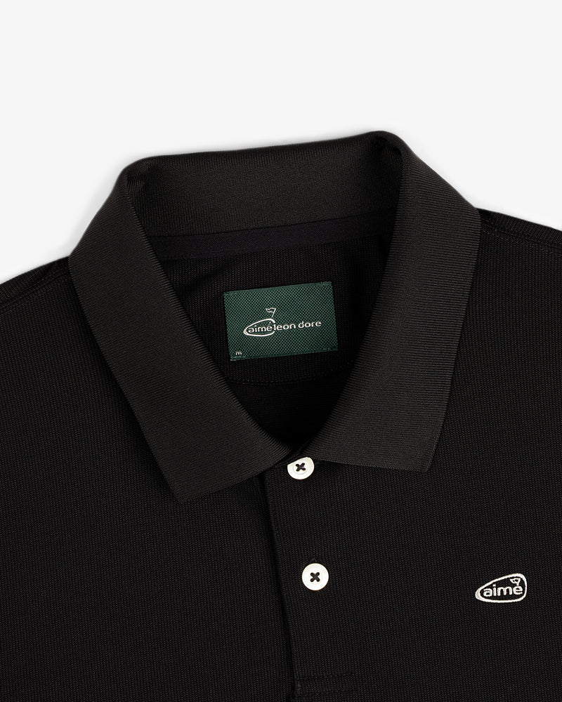 ALD Golf Polo: black collared shirt with white buttons and Aimé Leon Dore logo patch on the chest.