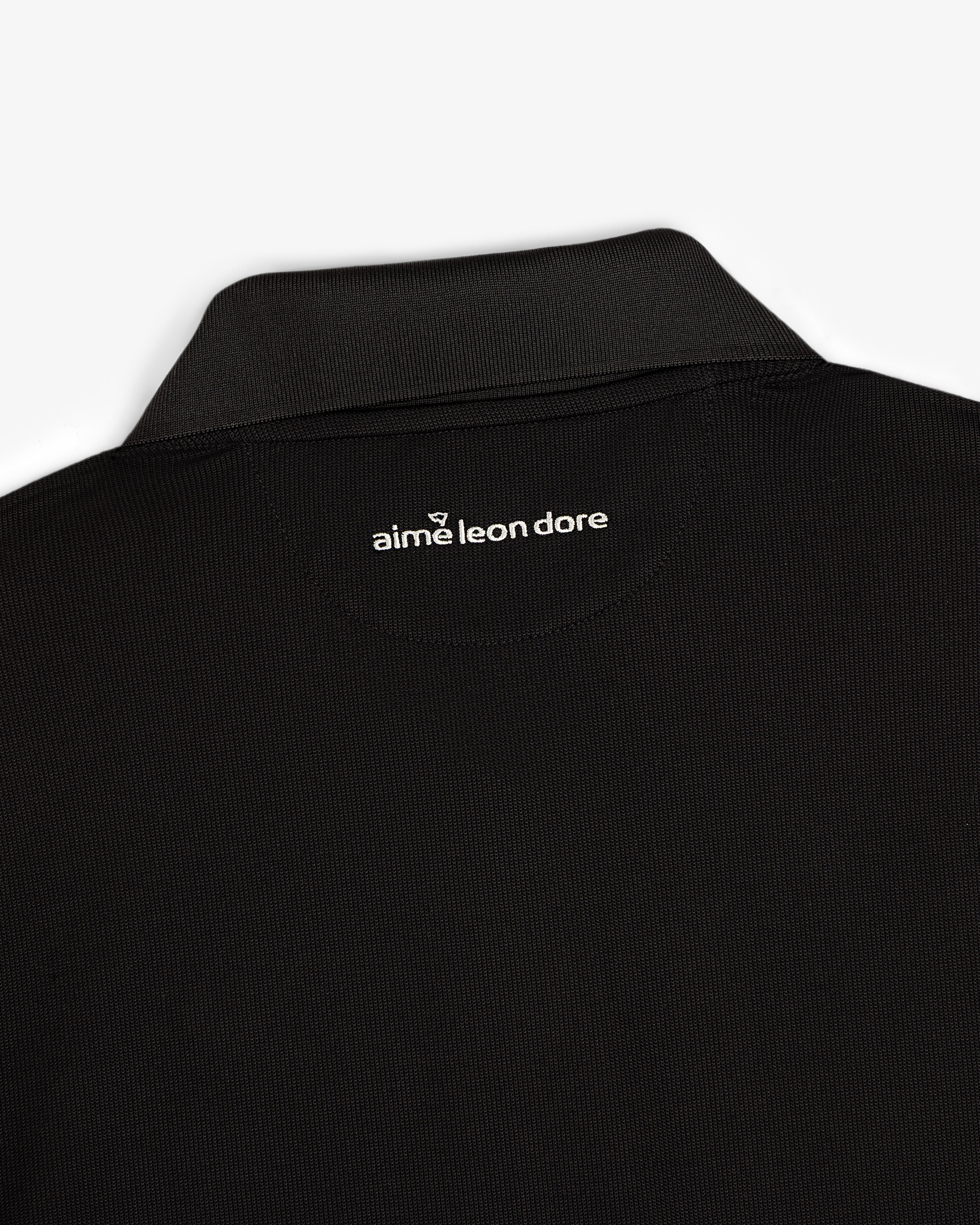 Close-up of the back collar of the ALD Golf Polo with "aime leon dore" printed in white below the neckline.