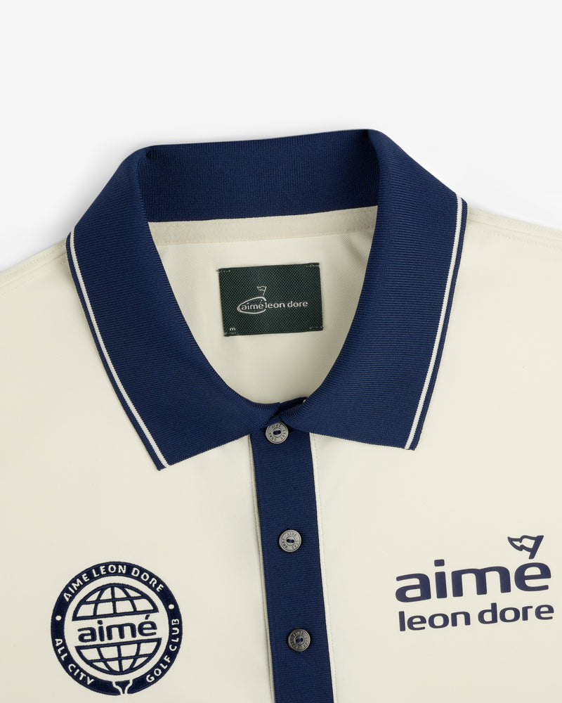 Cream ALD Golf Tour Polo with navy collar, Aimé Leon Dore logo and globe chest graphic, shown flat.