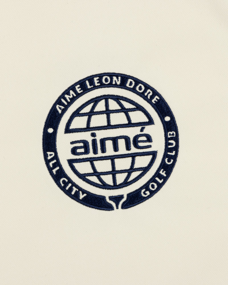 Navy blue globe logo with “AIMÉ LEON DORE ALL CITY GOLF CLUB” and “aimé” on cream ALD Golf Tour Polo.