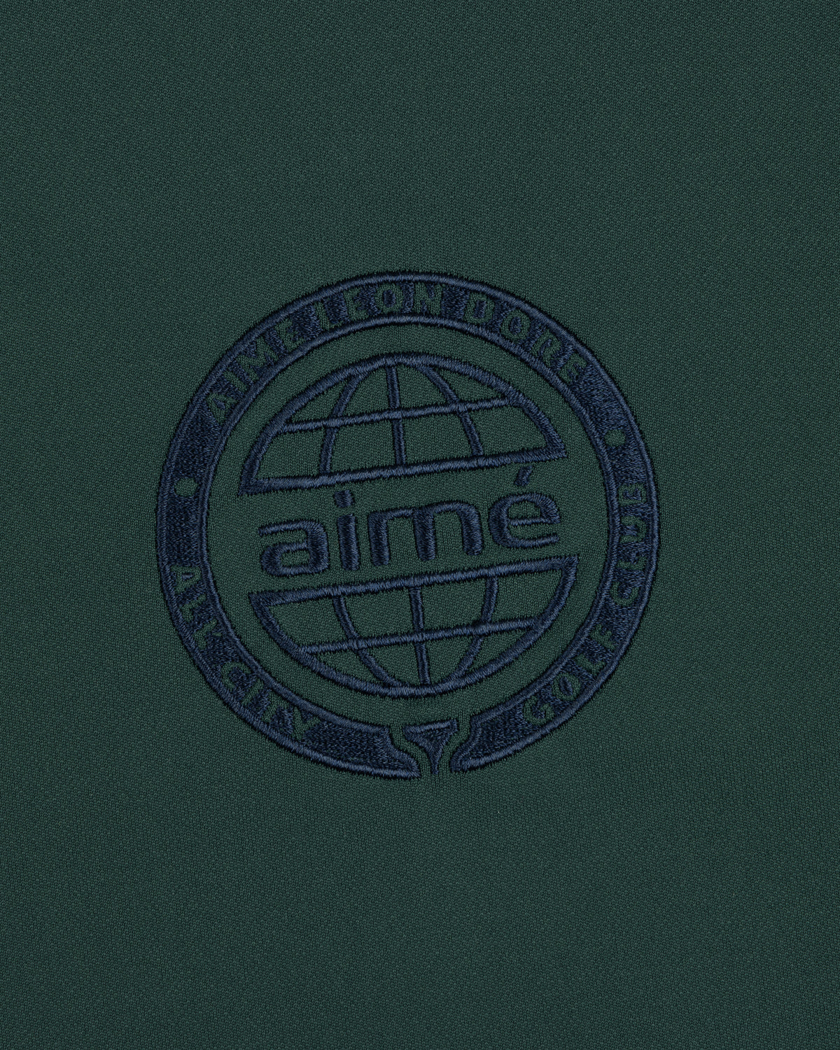 The ALD Golf Tour Polo features dark green fabric with a navy globe logo and Aimé Leon Dore All City Golf Club text.