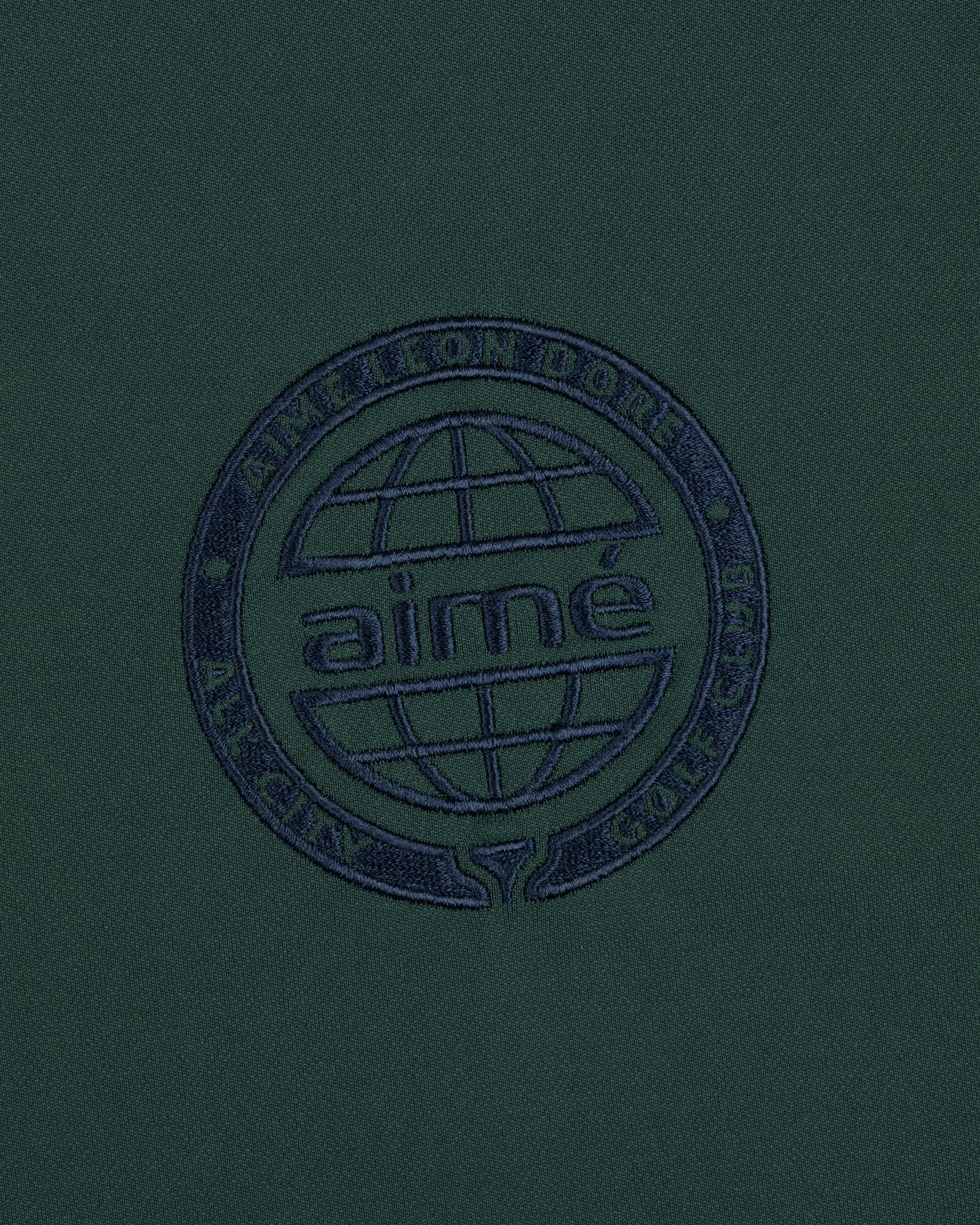 The ALD Golf Tour Polo features dark green fabric with a navy globe logo and Aimé Leon Dore All City Golf Club text.