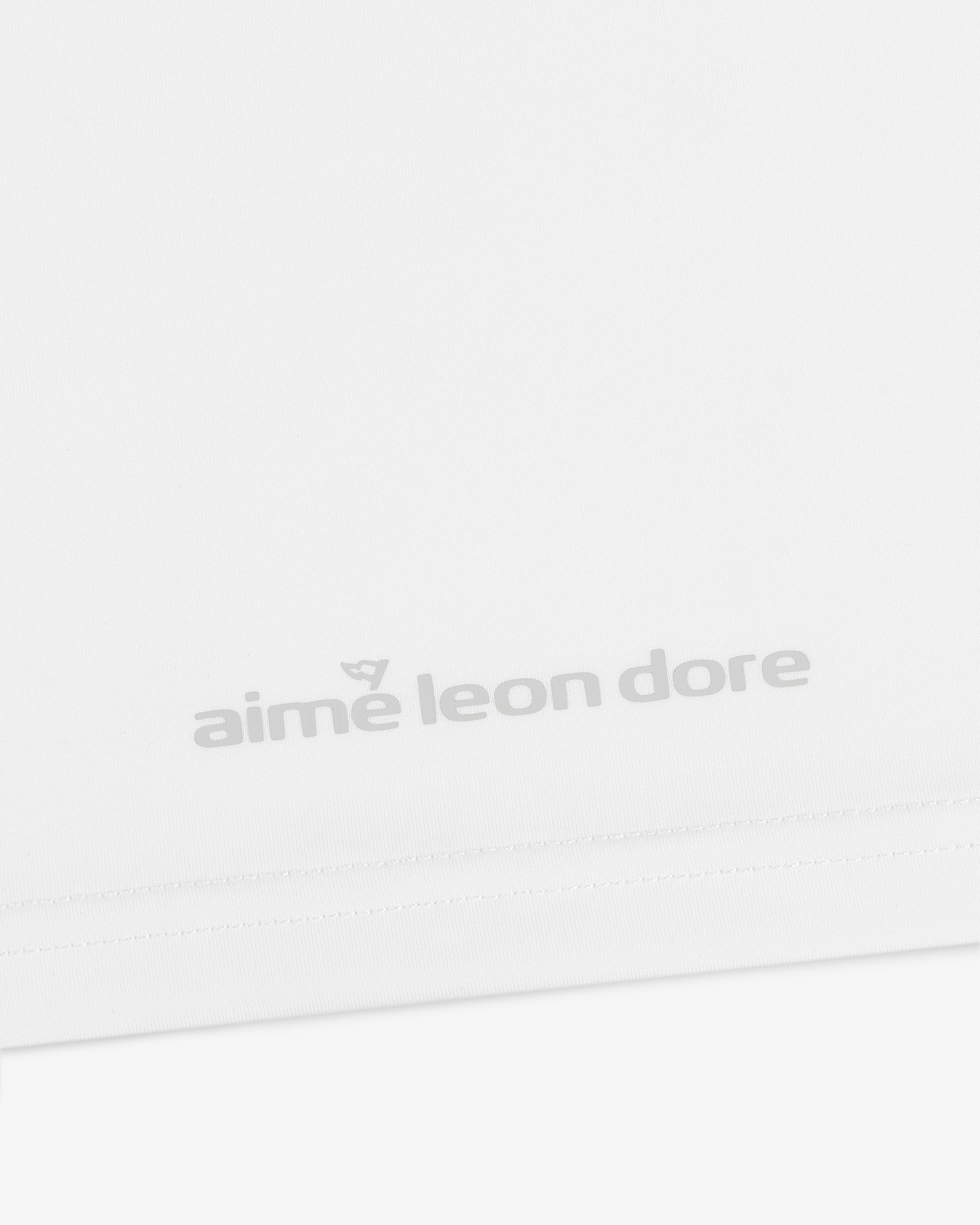 Close-up of the ALD Golf Performance Tee's white fabric featuring gray "aime leon dore" text near the bottom edge.