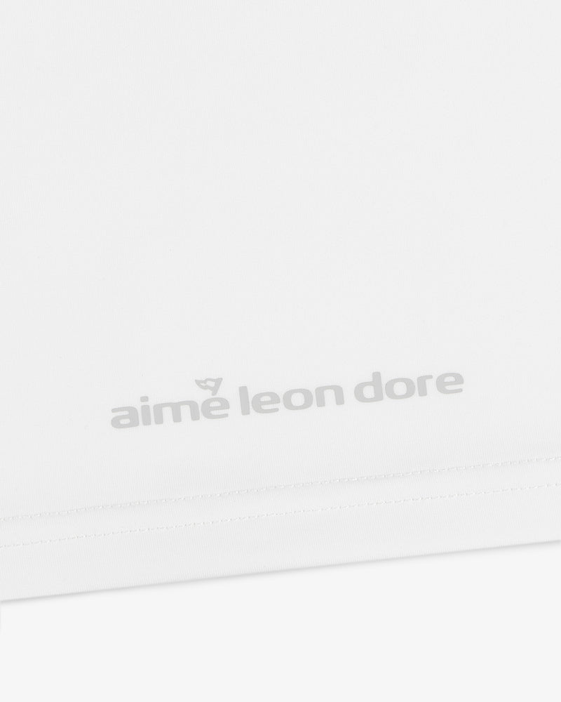 Close-up of the ALD Golf Performance Tee's white fabric featuring gray "aime leon dore" text near the bottom edge.