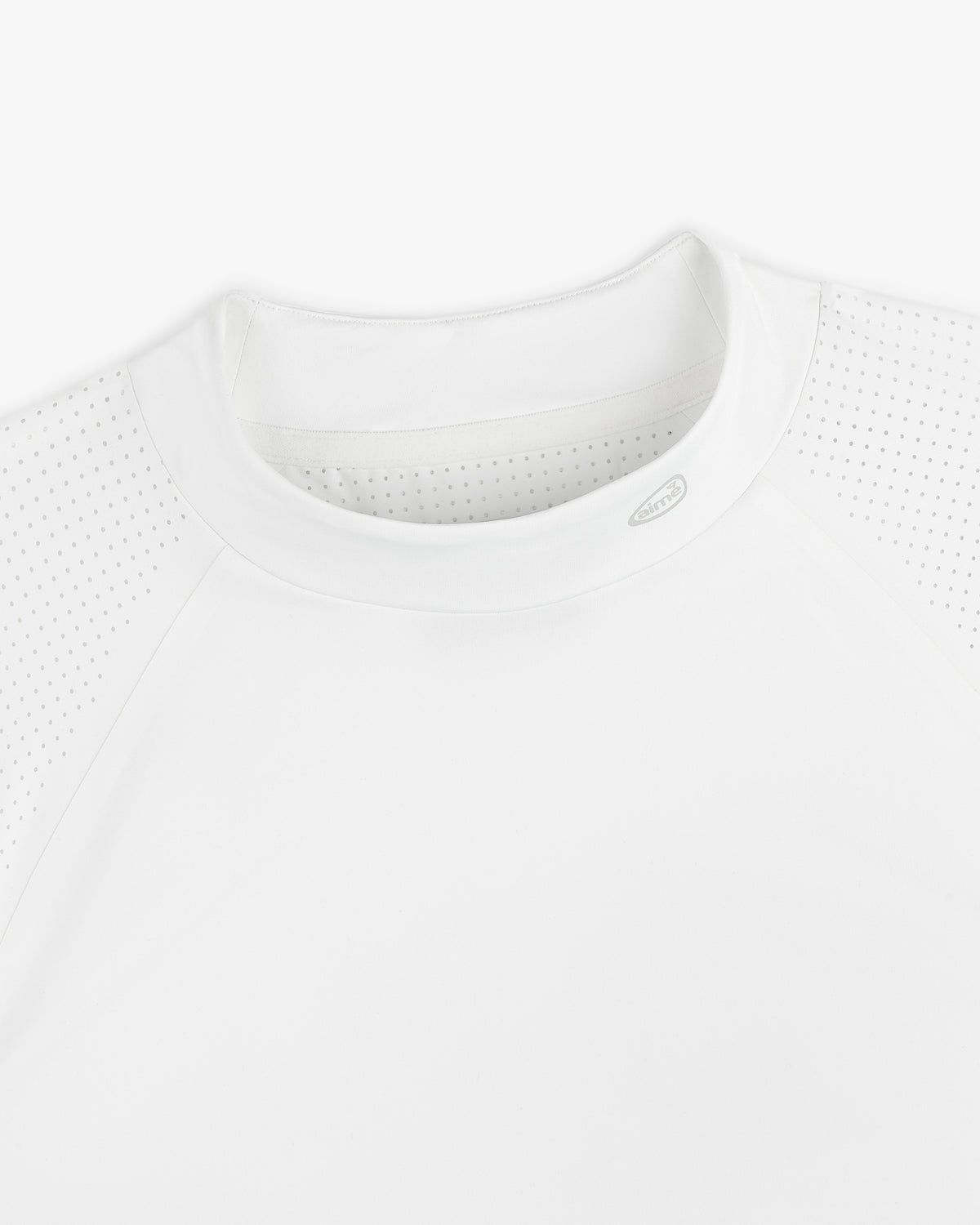 Close-up of the ALD Golf Performance Tee, a white athletic shirt with perforated shoulders and a round neck, laid flat.
