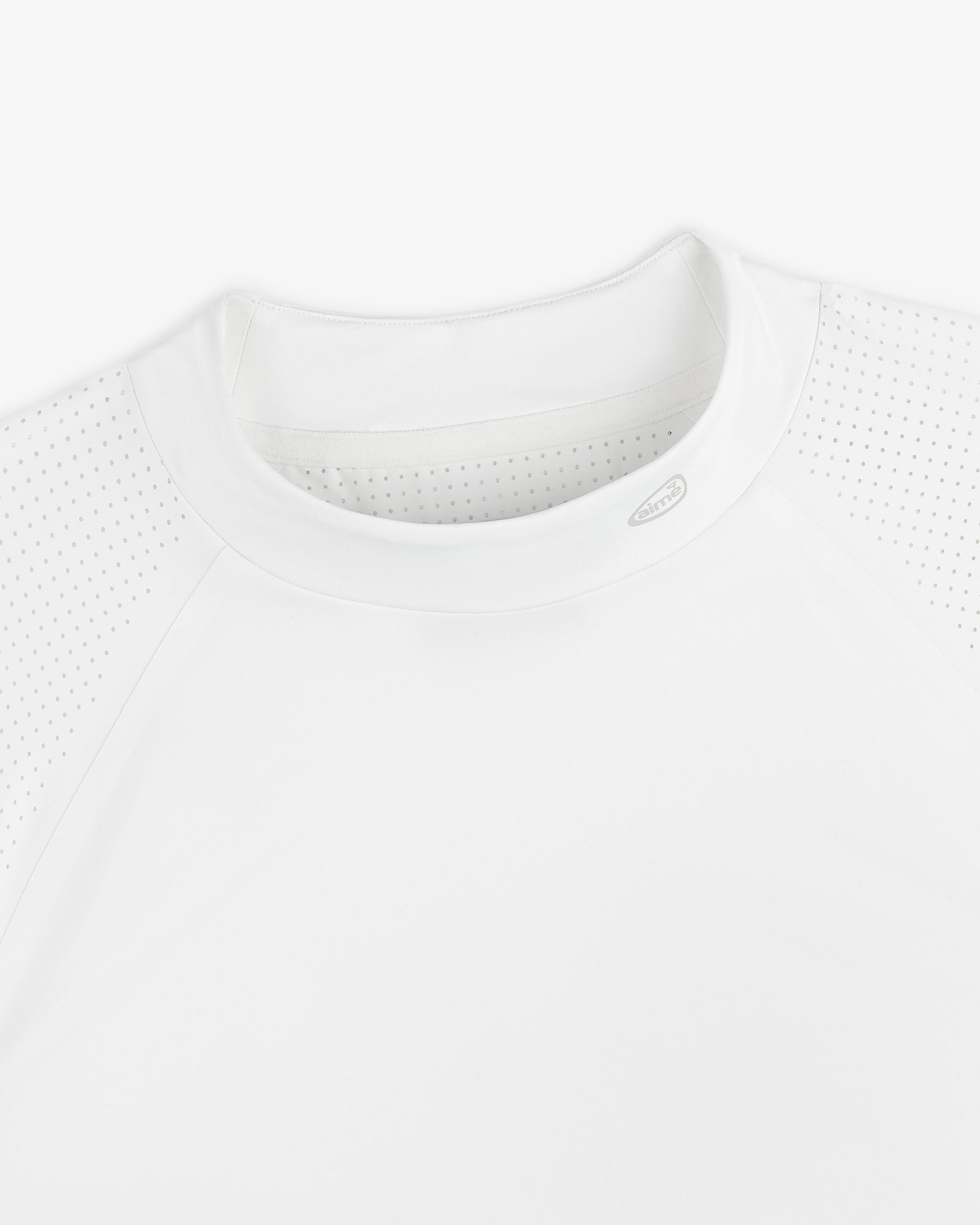 Close-up of the ALD Golf Performance Tee, a white athletic shirt with perforated shoulders and a round neck, laid flat.