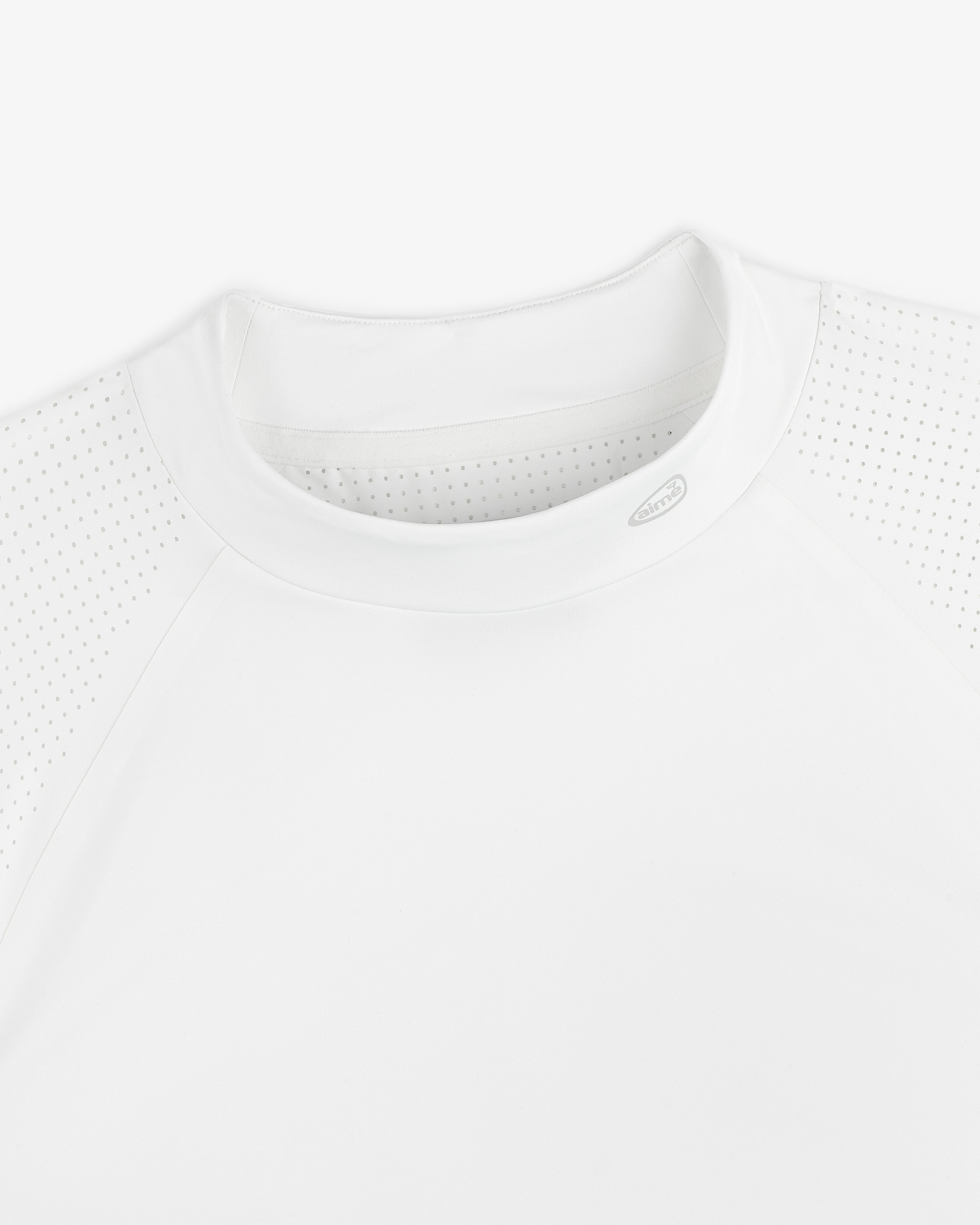 Close-up of the ALD Golf Performance Tee, a white athletic shirt with perforated shoulders and a round neck, laid flat.