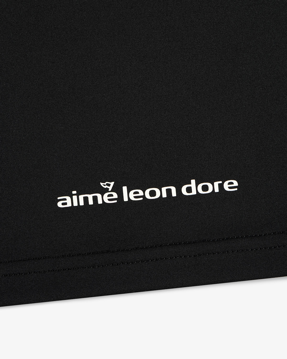 Black ALD Golf Performance Tee featuring white “aime leon dore” text and a small logo above the brand name.