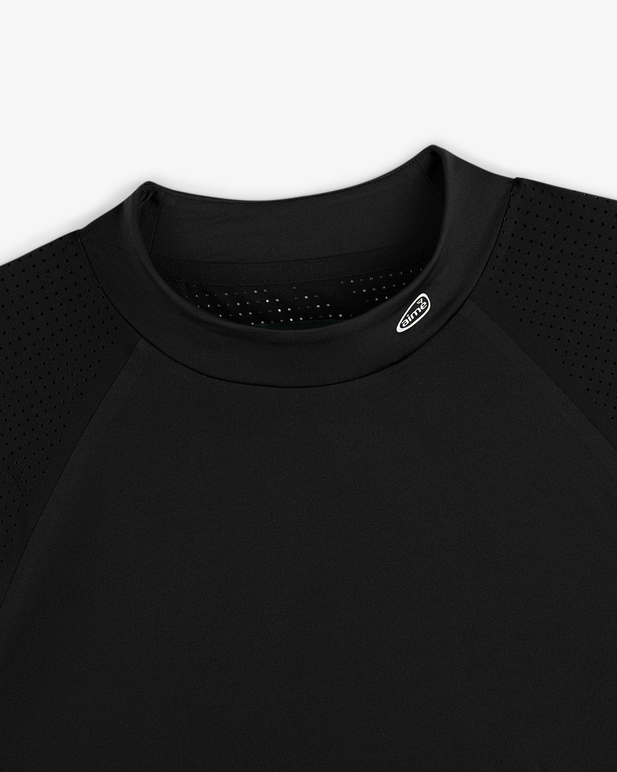 Close-up of the ALD Golf Performance Tee, a black shirt with perforated shoulders and a small oval logo by the collar.