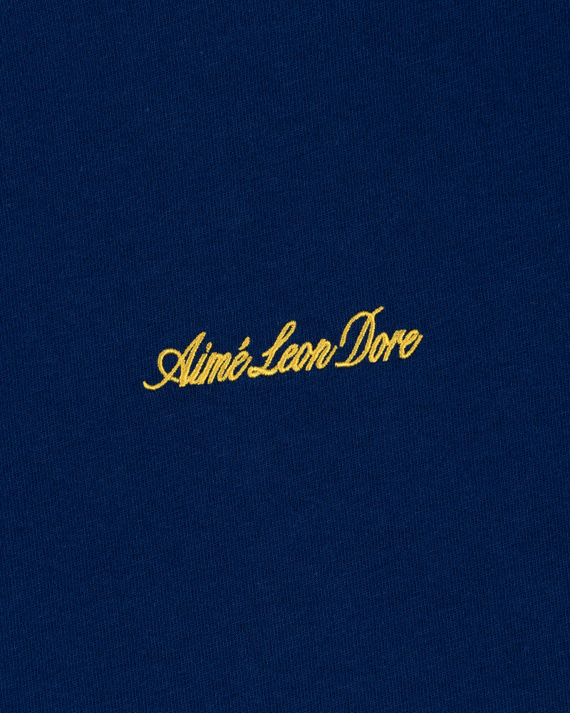 Yellow Aimé Leon Dore script logo on blue Embroidered Logo Tee.