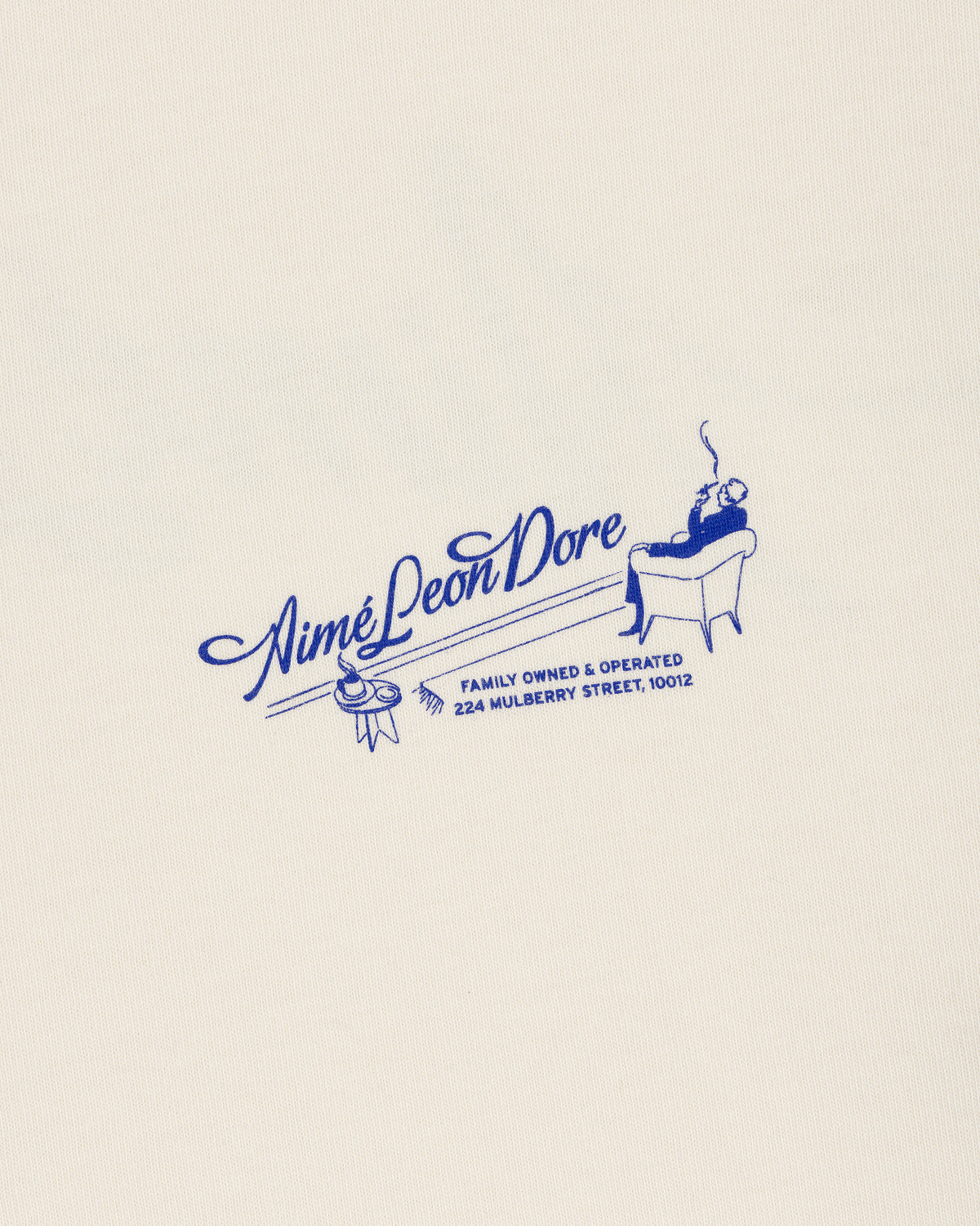 A blue Pappoús Logo Tee by Aimé Leon Dore features a lounging figure and 224 Mulberry Street on a cream background.
