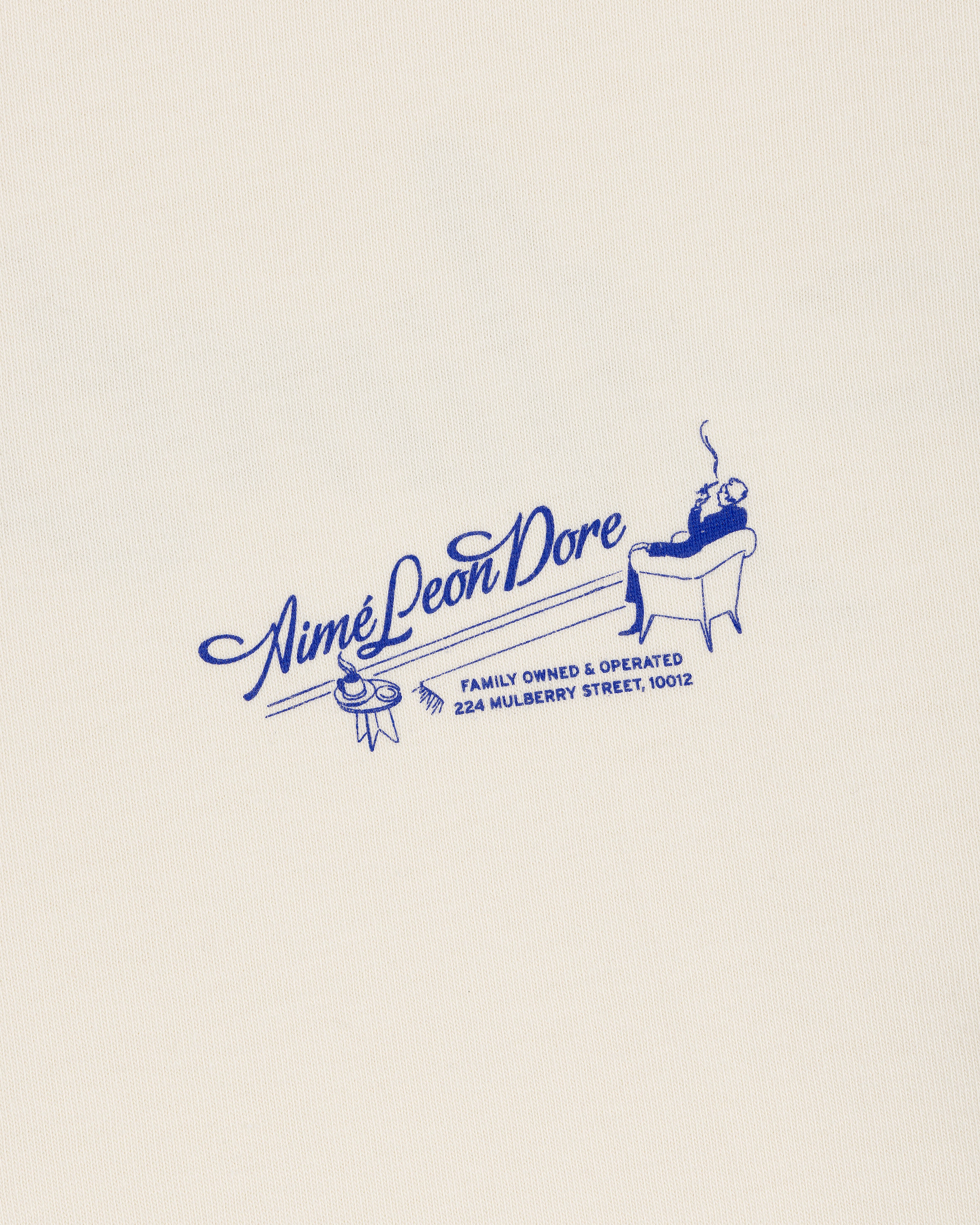 A blue Pappoús Logo Tee by Aimé Leon Dore features a lounging figure and 224 Mulberry Street on a cream background.