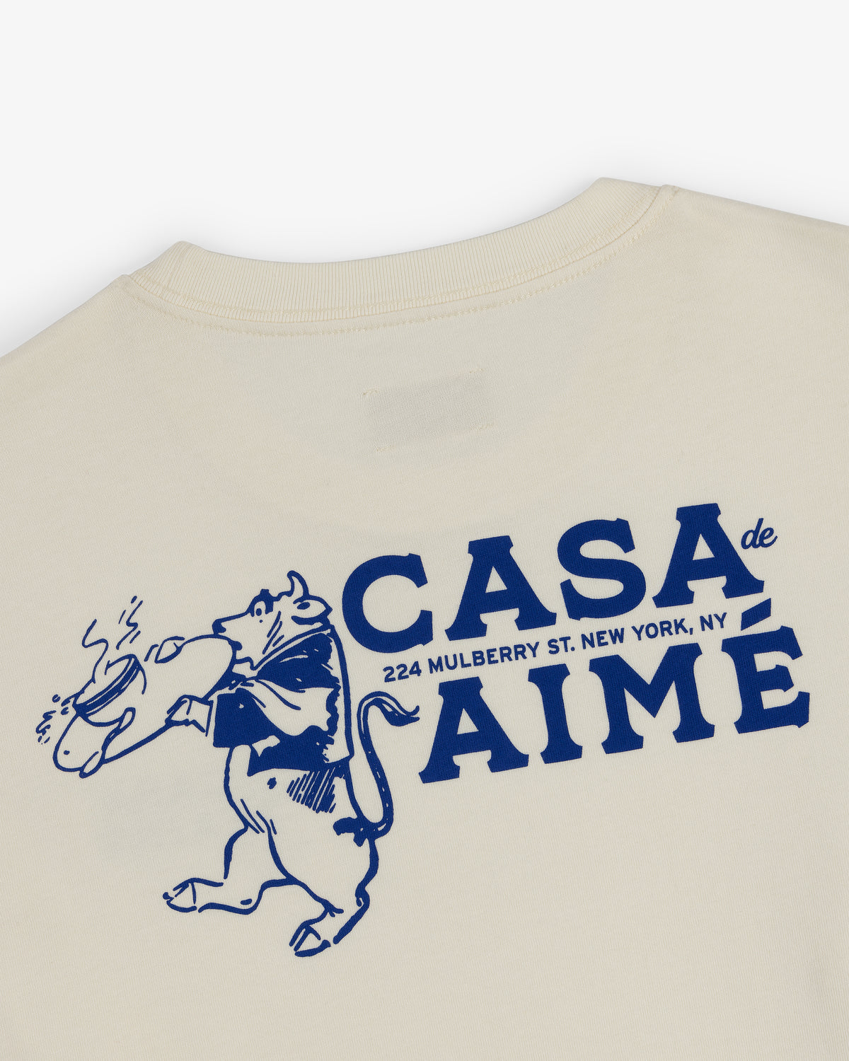 Beige Long-Sleeve Casa Tee with blue bull and bread graphic; CASA DE AIMÉ & New York address printed on the back.