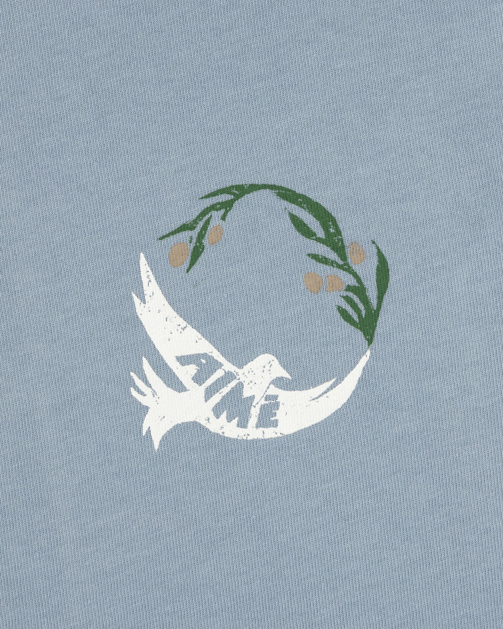 Woodblock Dove Tee features a white dove with TIME on its wing, flying beneath a green olive branch on light blue.