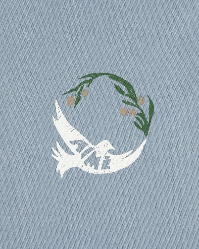 Woodblock Dove Tee features a white dove with TIME on its wing, flying beneath a green olive branch on light blue.