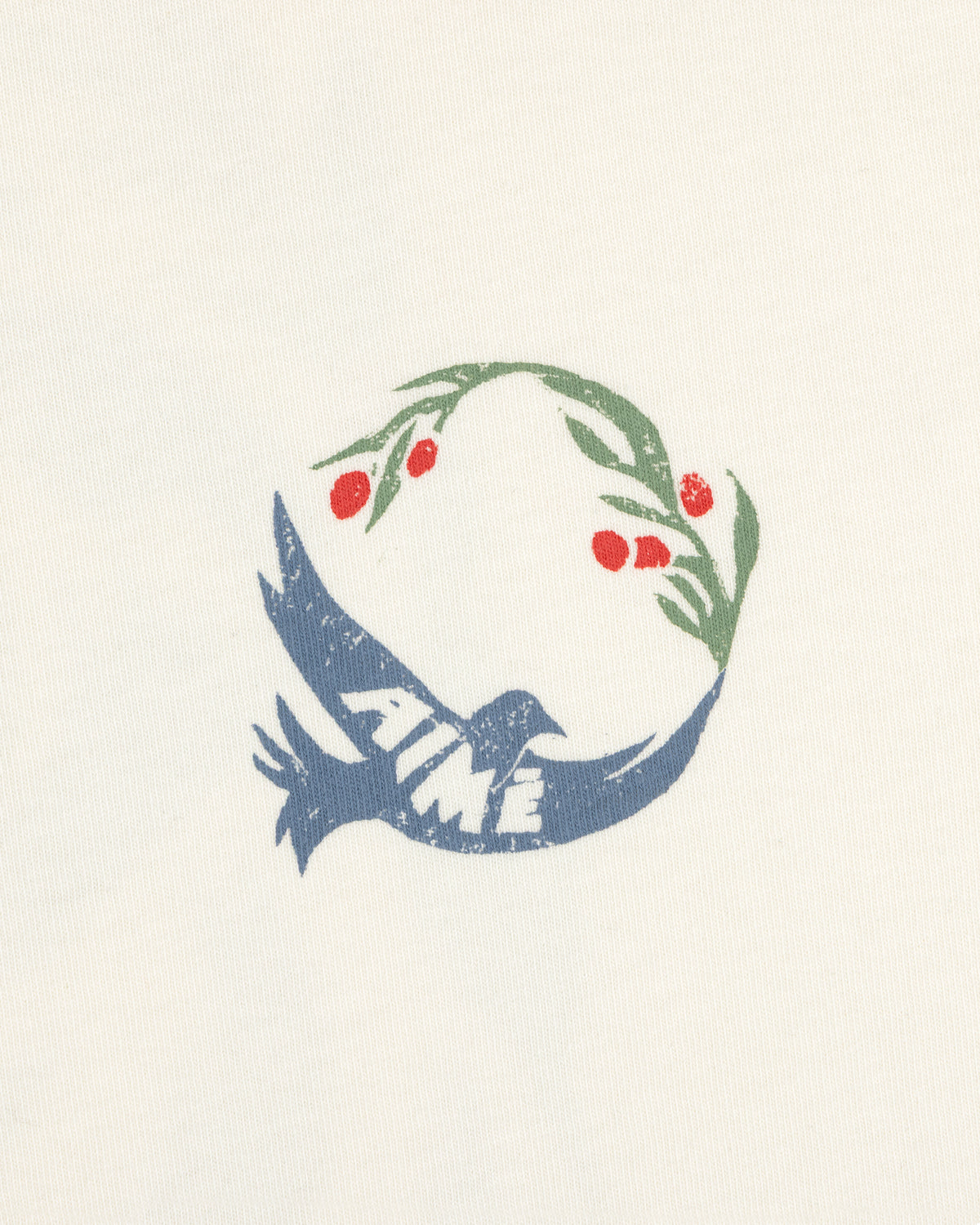 The Woodblock Dove Tee features a blue bird with AIMÉ, holding an olive branch with red berries on a cream background.