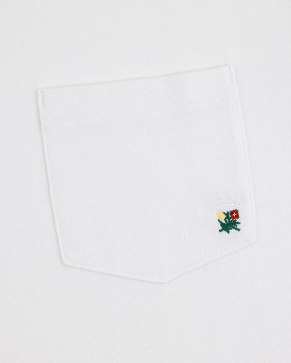 Crest Pocket Tee with a small green dragon embroidered on the pocket and "AIMÉ" stitched above in white.