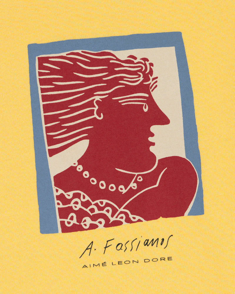 Stylized red and white figure with flowing hair on yellow, blue frame. "Fassianos Portrait Tee" by Aimé Leon Dore.