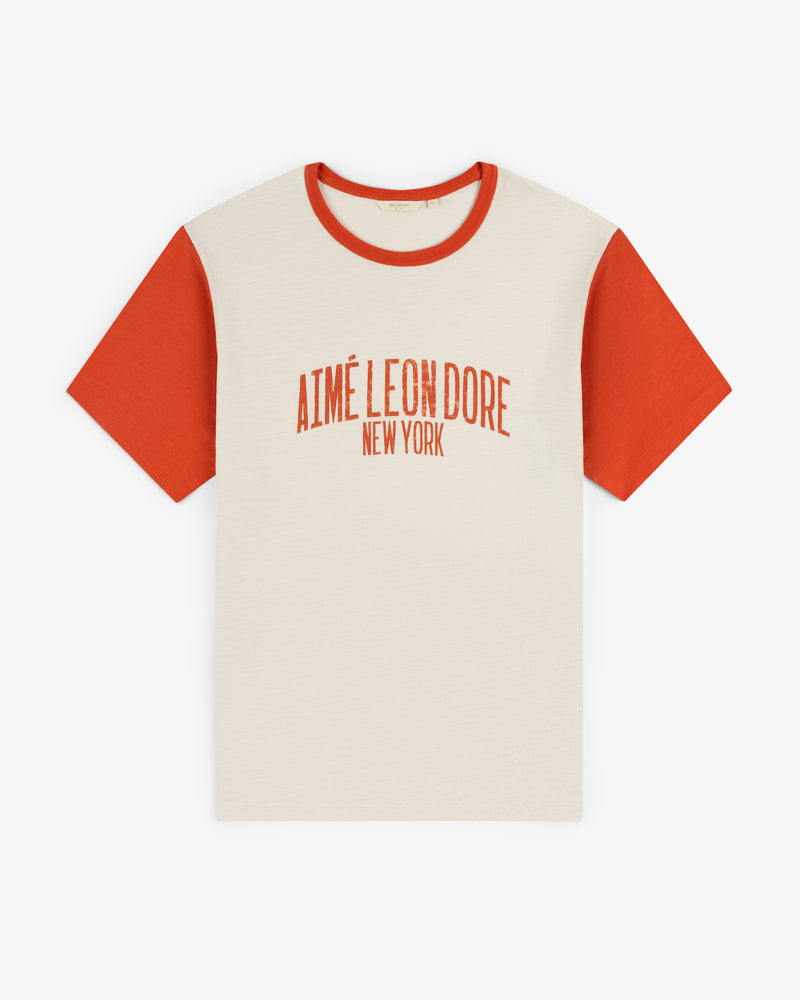 Washed Ringer Tee: cream T-shirt with red sleeves and “Aimé Leon Dore New York” red text on the front.