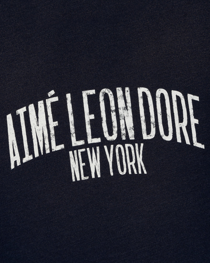 White text reads AIMÉ LEON DORE NEW YORK on the Washed Ringer Tee’s dark fabric background.