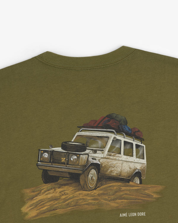 Safari Tee in olive green featuring a muddy SUV with luggage and “AIMÉ LEON DORE” text below.