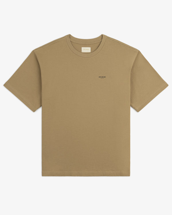 Safari Tee: tan short-sleeve shirt with a small chest logo, shown flat on a white background.
