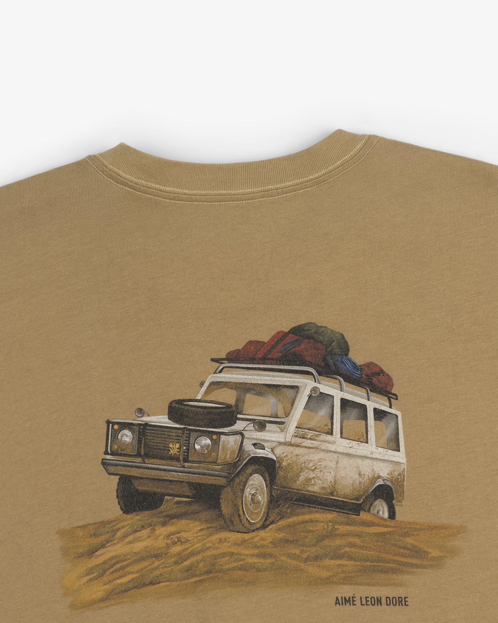 Illustration of a white SUV with luggage on sand, on the Safari Tee, with Aimé Leon Dore text below.