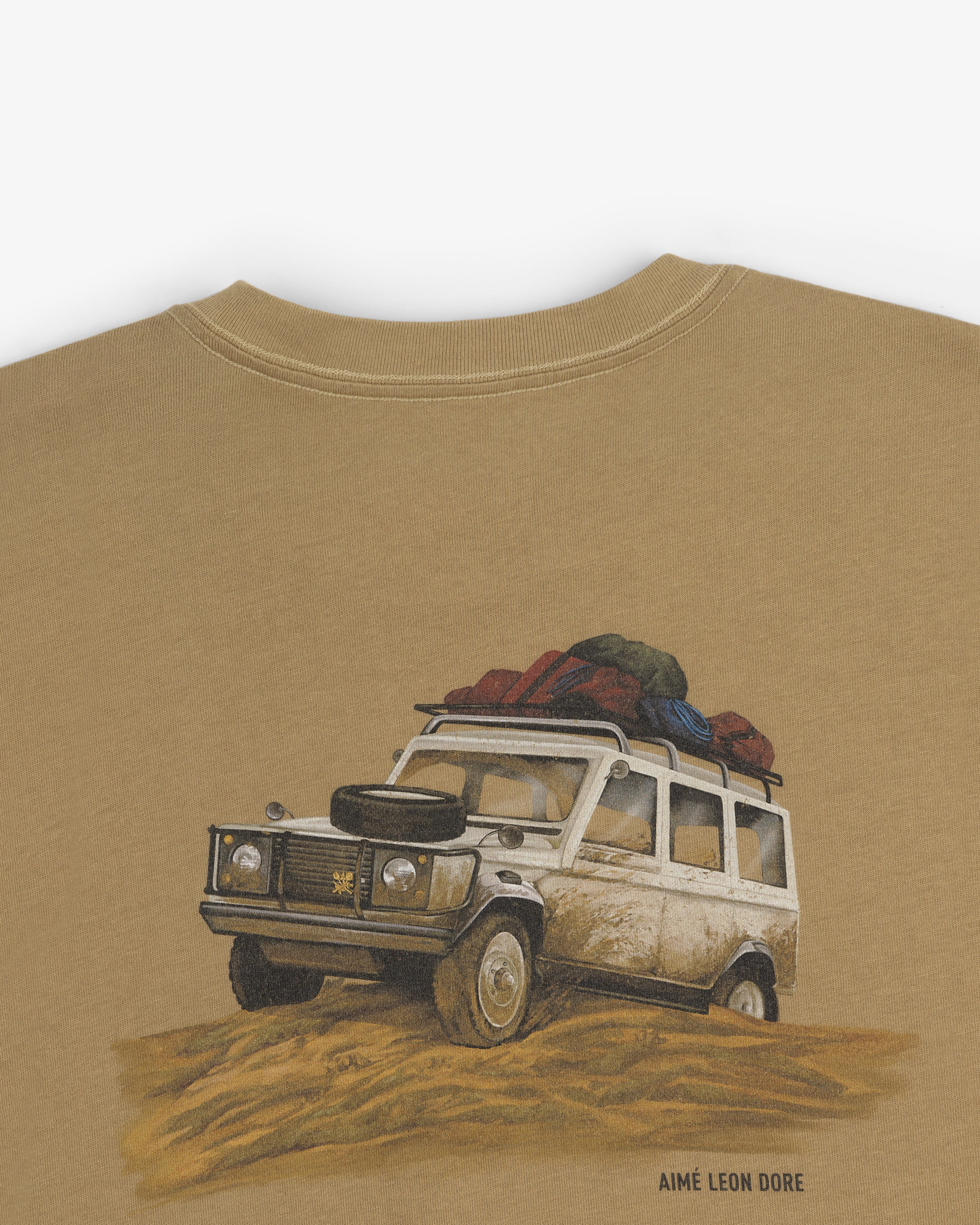 Illustration of a white SUV with luggage on sand, on the Safari Tee, with Aimé Leon Dore text below.