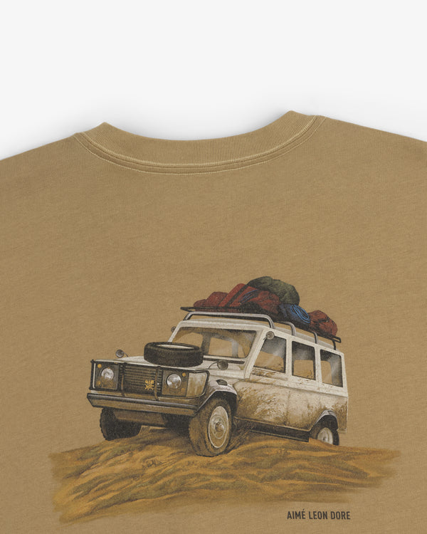 Illustration of a white SUV with luggage on sand, on the Safari Tee, with Aimé Leon Dore text below.