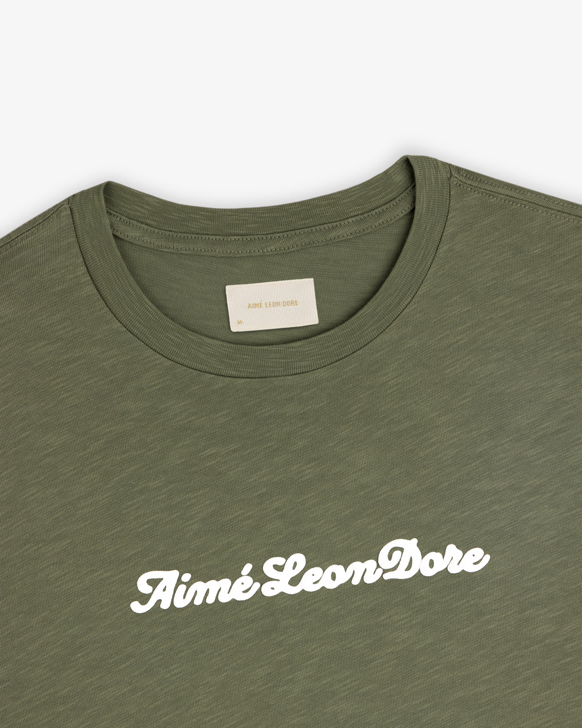 Olive green Puff Print Slub Logo Tee with Aimé Leon Dore in white script across the chest.