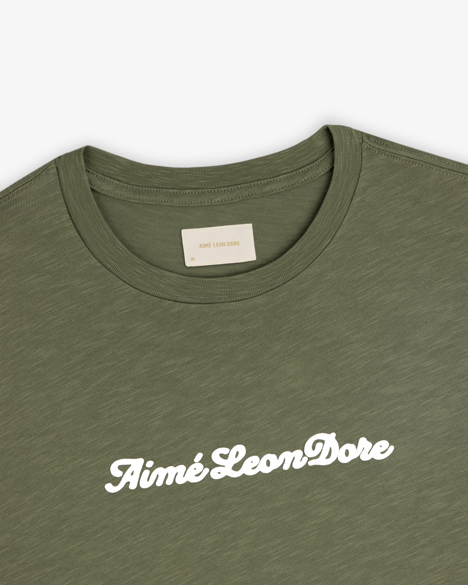 Olive green Puff Print Slub Logo Tee with Aimé Leon Dore in white script across the chest.