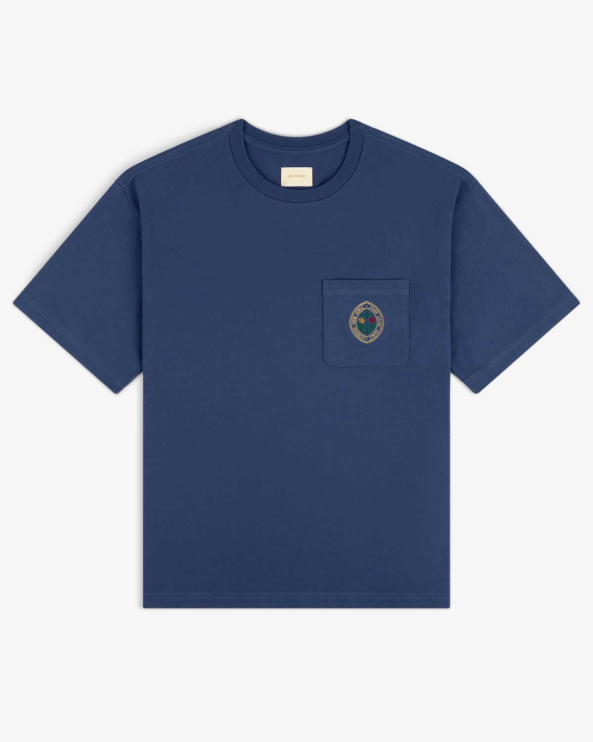 Botanical Crest Pocket Tee: blue short-sleeve shirt with small crest emblem on left chest pocket, shown on white background.
