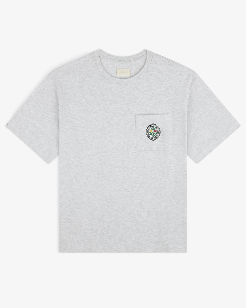 Light gray Botanical Crest Pocket Tee with short sleeves and a chest pocket featuring a small colorful crest.