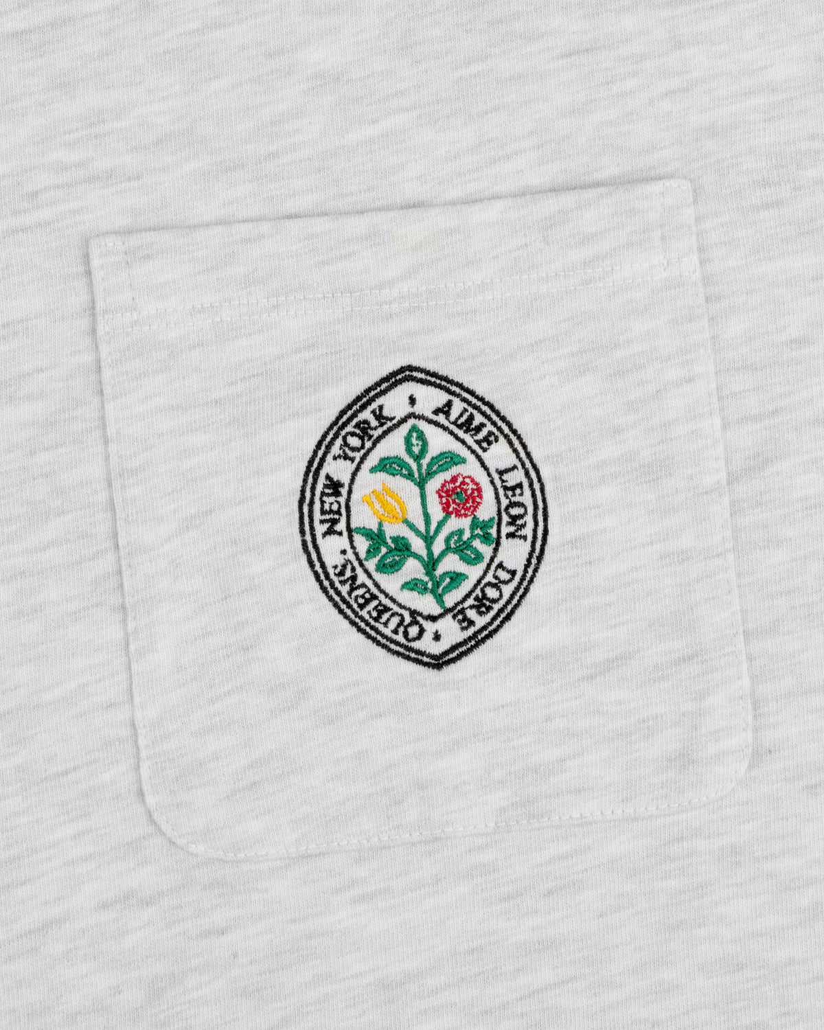 Botanical Crest Pocket Tee with a circular floral patch and “Aime Leon Dore New York Queens” text on the pocket.