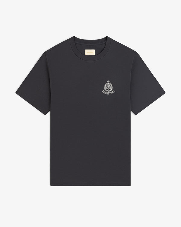 Saint George Graphic Tee: black short-sleeve shirt with a small ornate crest logo on the left chest, shown on white.