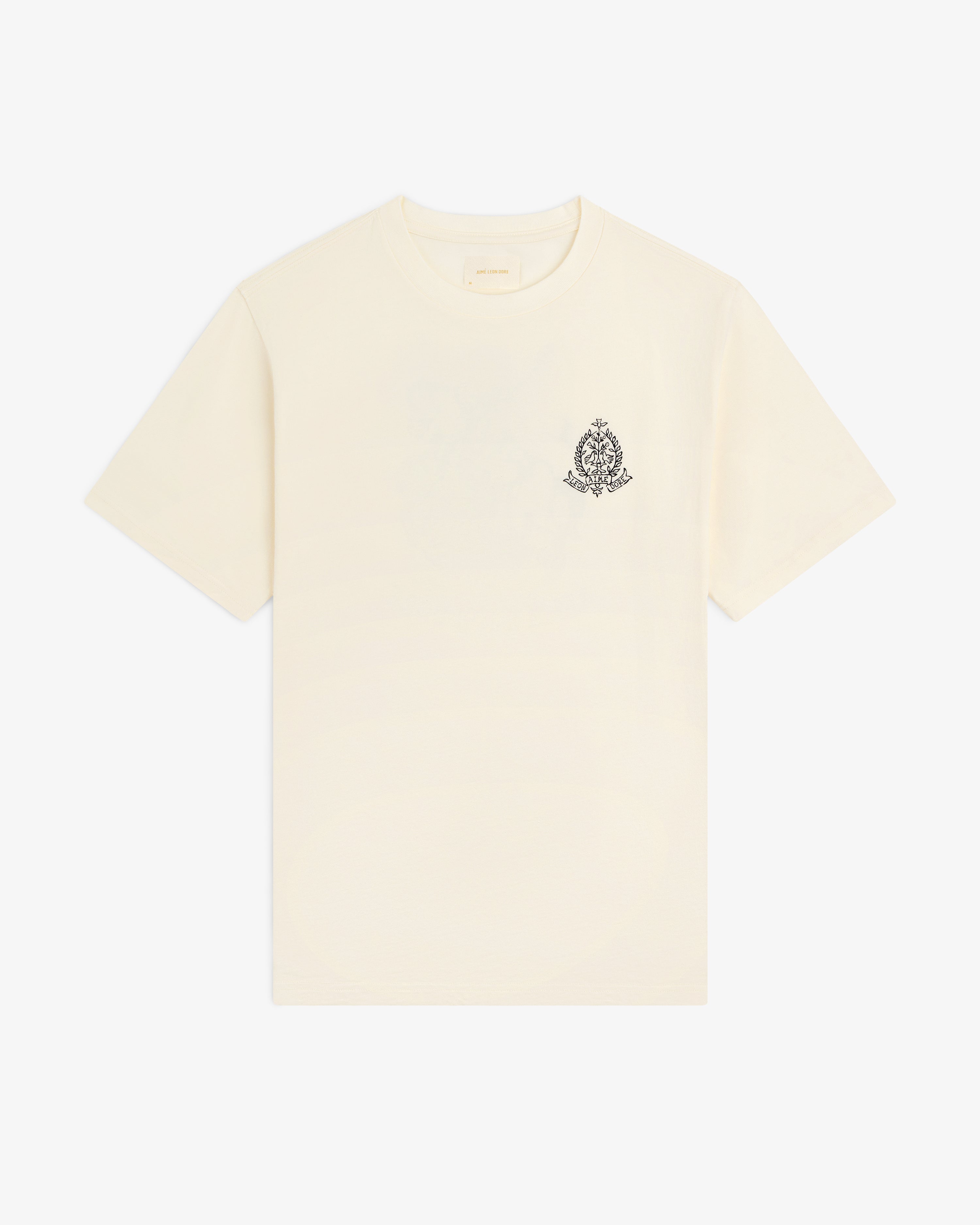 Saint George Graphic Tee: cream short-sleeve t-shirt with a small black ornate crest on the upper left chest.