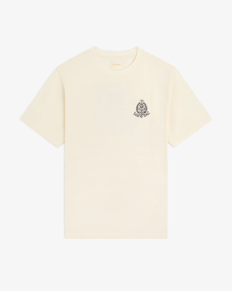 Saint George Graphic Tee: cream short-sleeve t-shirt with a small black ornate crest on the upper left chest.