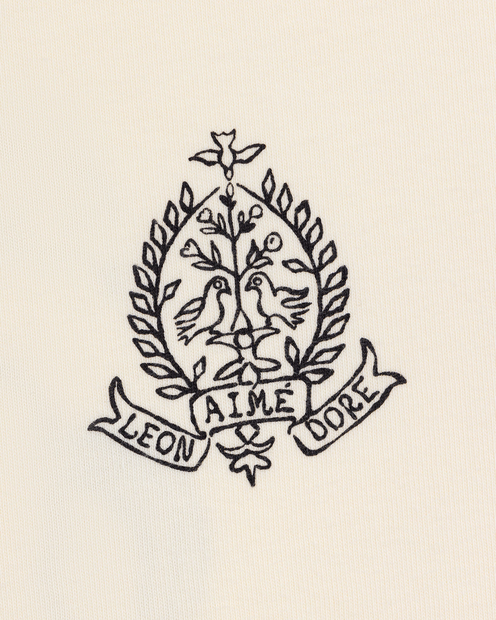 Cream Saint George Graphic Tee with embroidered crest featuring two birds, a tree, laurels, and “Aime Leon Dore” banner.