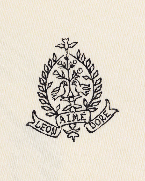 Cream Saint George Graphic Tee with embroidered crest featuring two birds, a tree, laurels, and “Aime Leon Dore” banner.